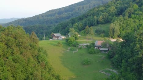 Farm-houses-up-in-hills-surrounded-with-green-meadows-and-spruce-forest