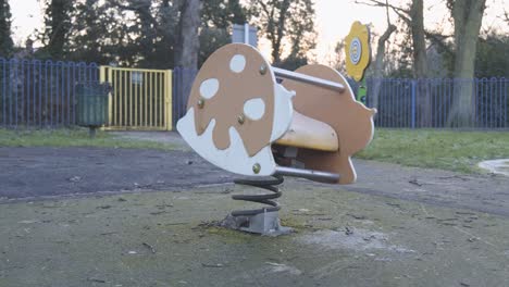 un juguete de resorte que rebota en un parque infantil vacío en un frío día nublado en el centro de londres