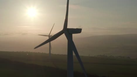 una vista aérea de las turbinas eólicas girando lentamente con el sol vespertino detrás de ellas, aberdeensire, escocia