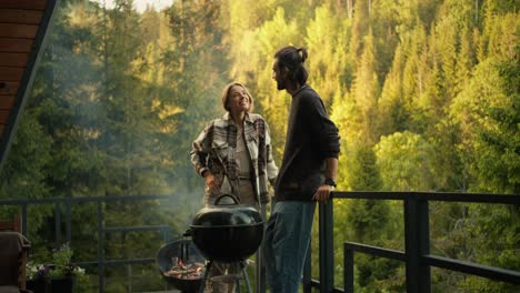 a brunette guy and a blonde girl flirt and chat at a picnic in a coniferous green forest. camping in the mountains