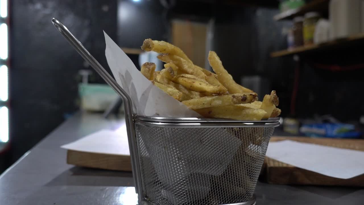 Close-up shot of a chef placing a burger onto a board alongside a portion of fries
