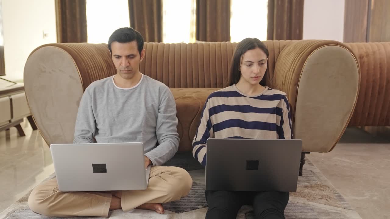 Pasangan India bekerja dari rumah menggunakan laptop