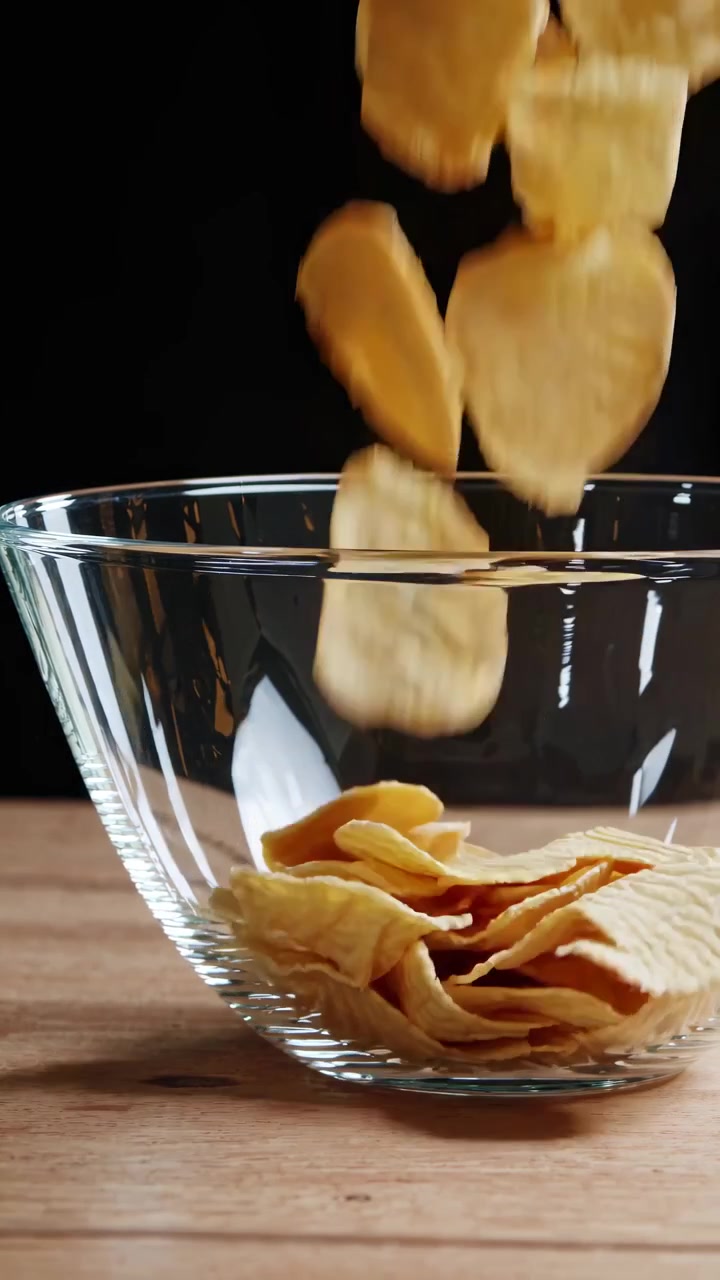 Potato Chips Falling Into a Glass Bowl