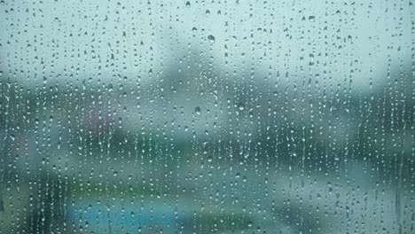 rain water drops falling down on the window glass , rain drops on the windows glass, close shot of water droplets falling .