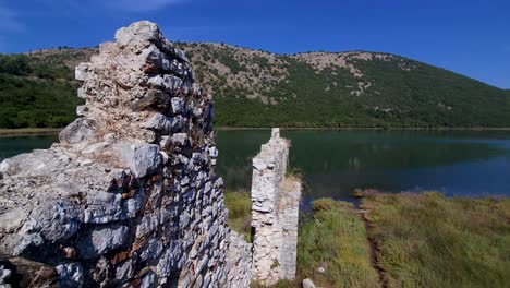 old ruined stone walls and an ancient castle rest on the shores of butrint lake, an archaeological marvel