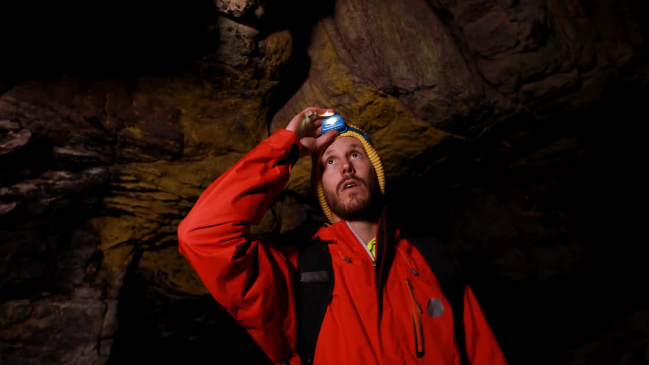 Lodret video: Mand holder lampe og scanner hule, mens strålen får badges til at svæve og vise vækst.
