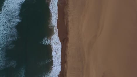 Ojo-De-Pájaro,-Tiro-Con-Dron-Del-Puerto-Sándwich-En-Namibia---El-Dron-Está-Siguiendo-La-Costa-Donde-El-Desierto-Se-Encuentra-Con-El-Océano