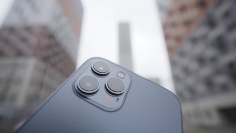 closeup of a smartphone camera lens with city buildings in the background