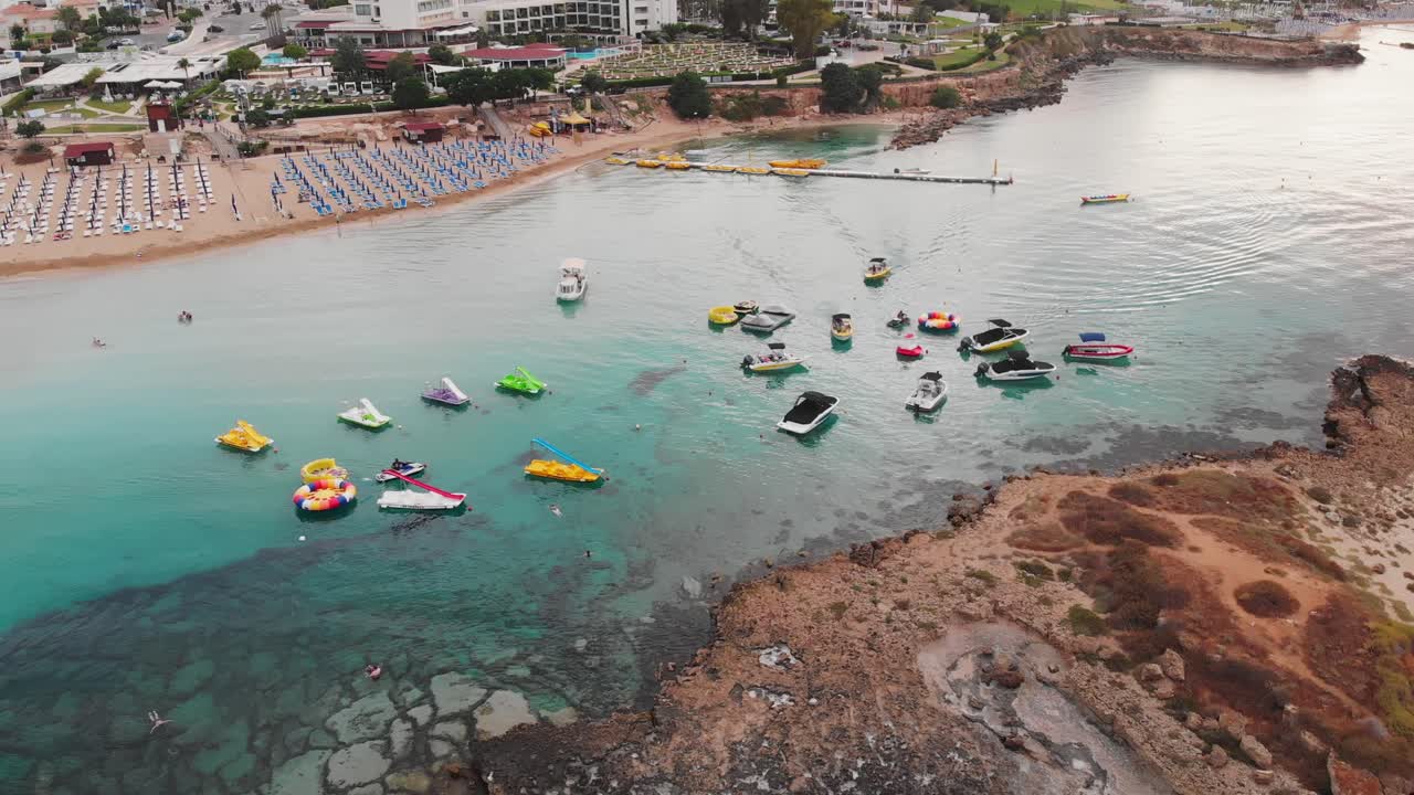Persone che parcheggiano barche per sport acquatici vicino all'isola al tramonto. Protaras, Cipro