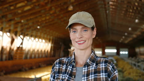 close-up view of young caucasian woman with cap looking at camera in stable with sheep flock