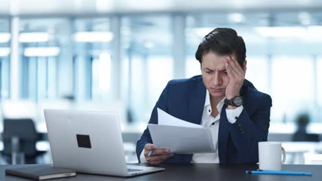 tensed indian manager reading and signing reports