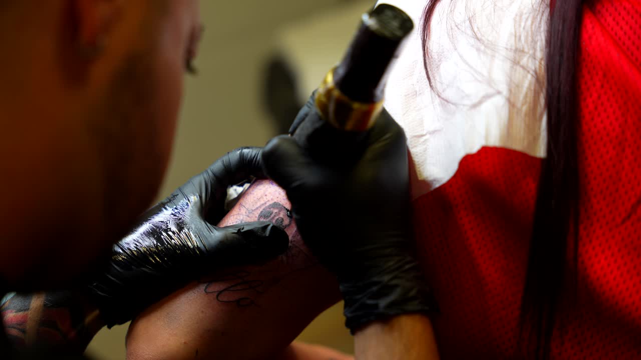 Tatuatore che sfuma meticolosamente il braccio superiore del cliente con inchiostro nero per un effetto realistico