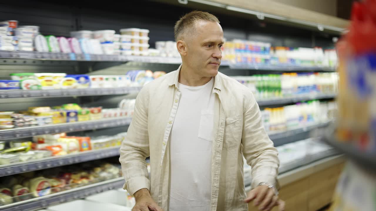 A middle-aged shot visitor chooses products in the dairy section. Product viewing and selection. Shopping