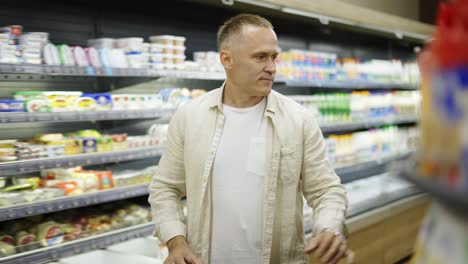 a middle-aged shot visitor chooses products in the dairy section. product viewing and selection. shopping