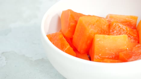 close-up of cubed papaya in a white bowl