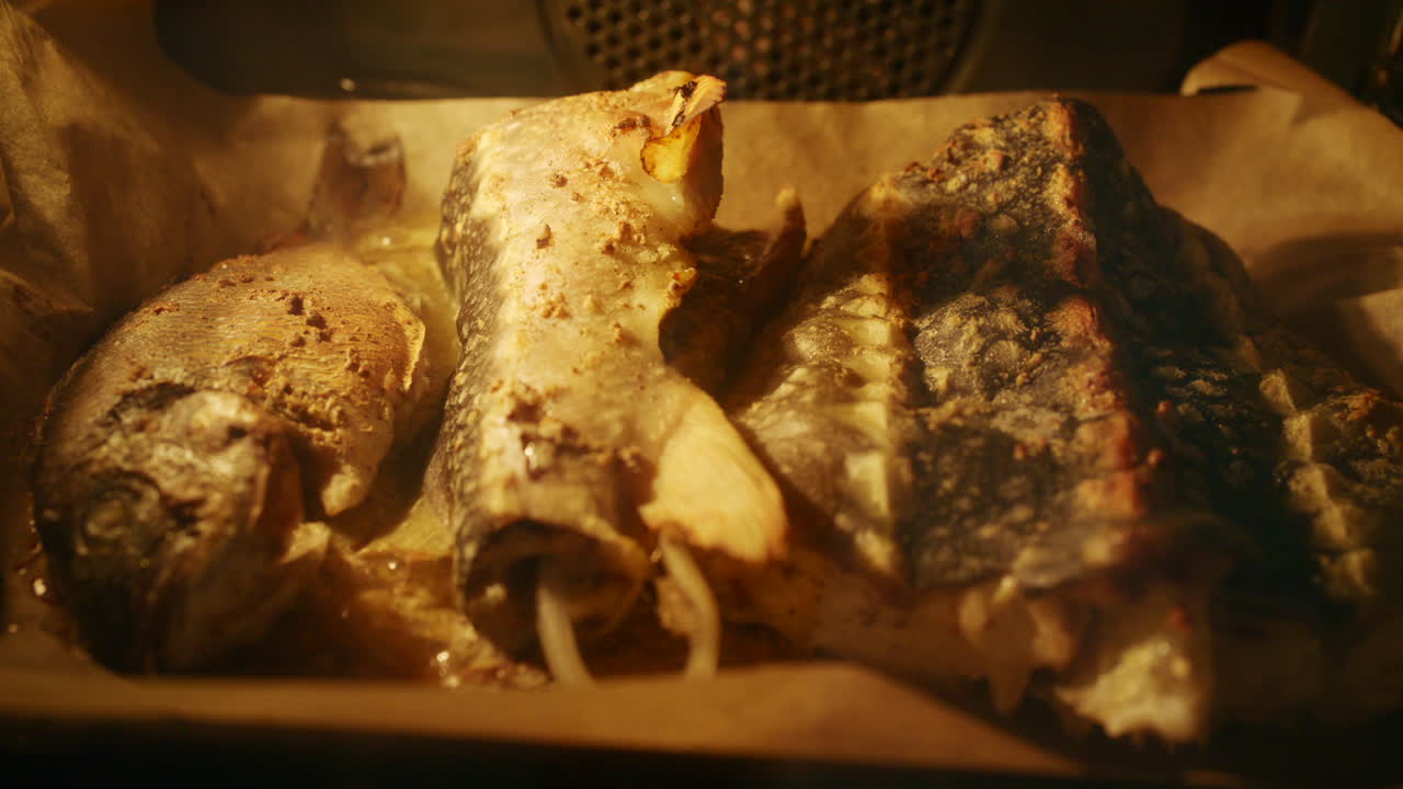 Fresh fish pieces roasting in the oven on a tray, golden surface and steam visible