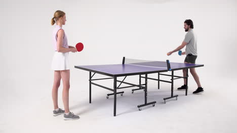 playing table tennis, man and woman enjoying game in studio setting