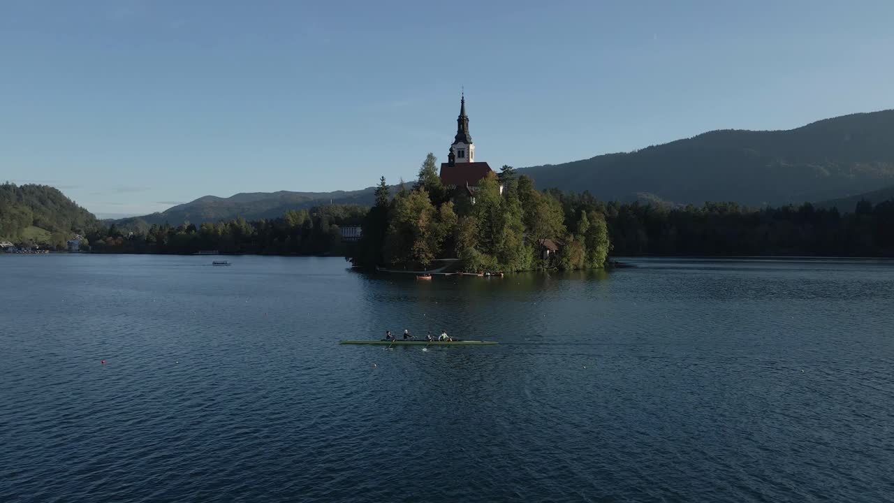 Veduta aerea della chiesa sull'isola del Lago di Bled e canottieri incorniciati dalle Alpi, Slovenia