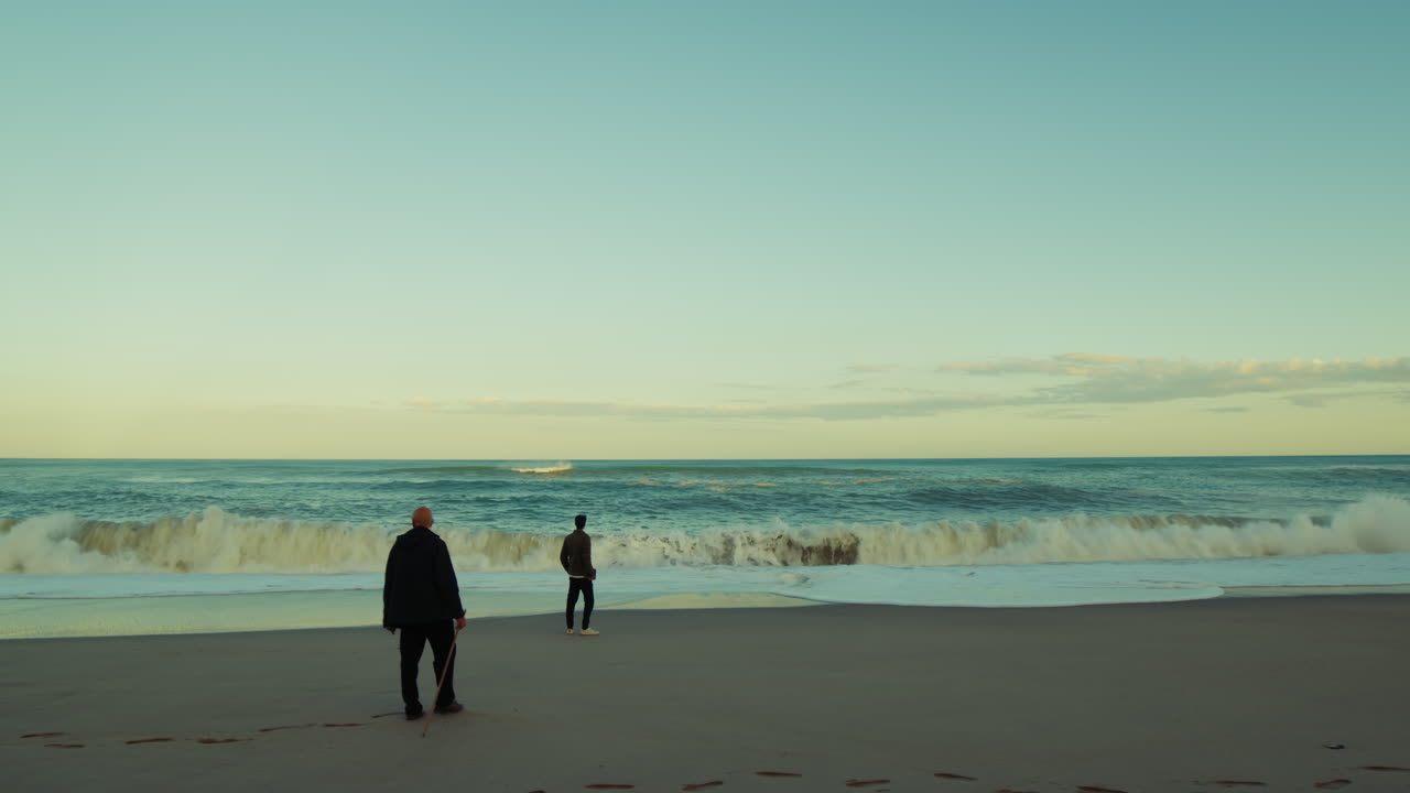 Two Distant Men Walk to Relax Their Minds Near the Stormy Waves Ocean