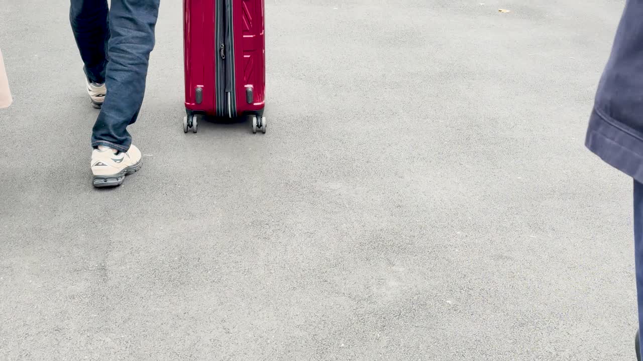 Una persona tira de una maleta de ruedas roja por un pavimento gris en Tokio, Japón.