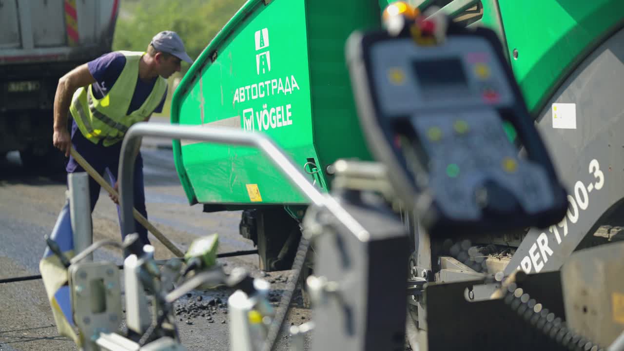 máquina profesional para compactar y nivelar los paseos del suelo a lo largo de la carretera bajo el control de los trabajadores