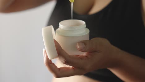 una mujer hispana adulta abre una botella de crema natural de aloe vera.