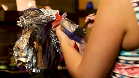 beautician applies purple hair dye