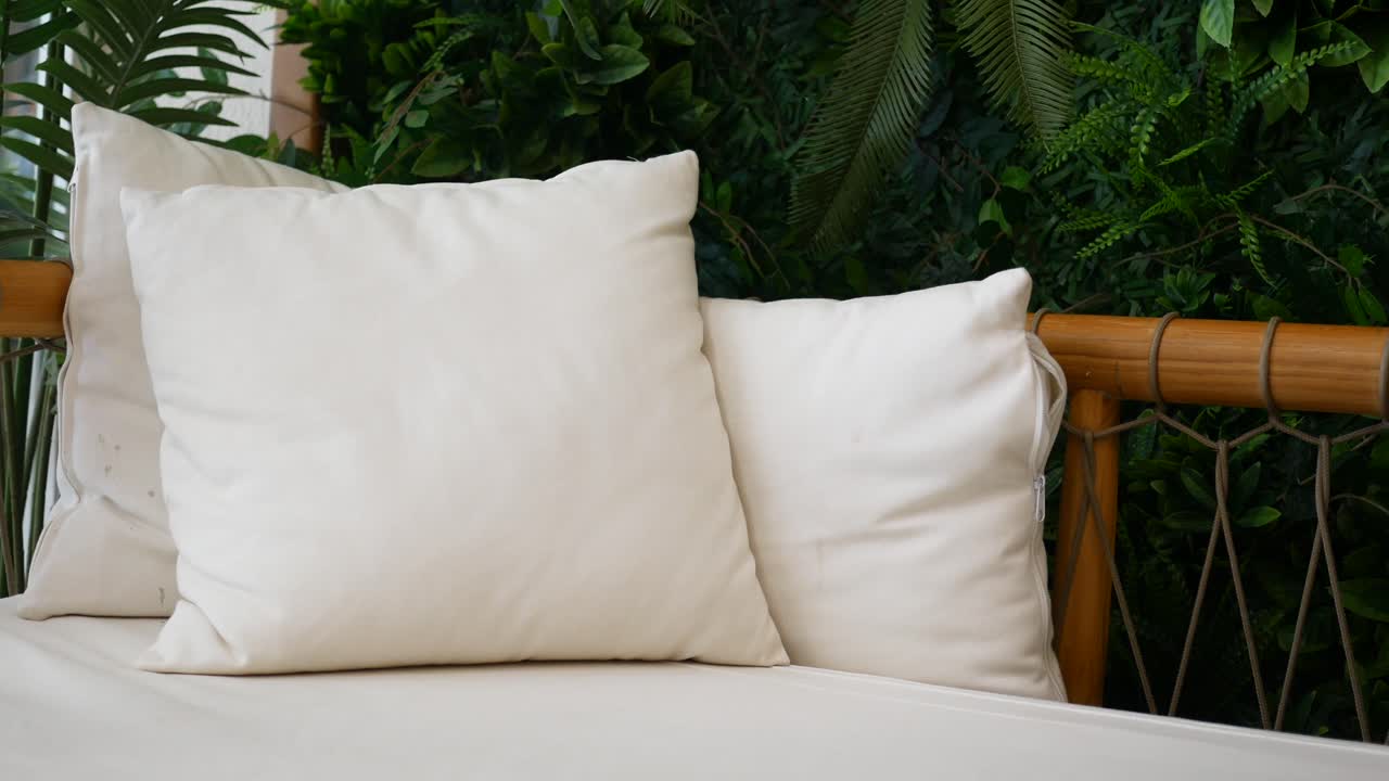 almohadas blancas en muebles al aire libre con plantas tropicales