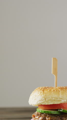video vertical de una hamburguesa casera fresca con ensalada en un fondo de madera