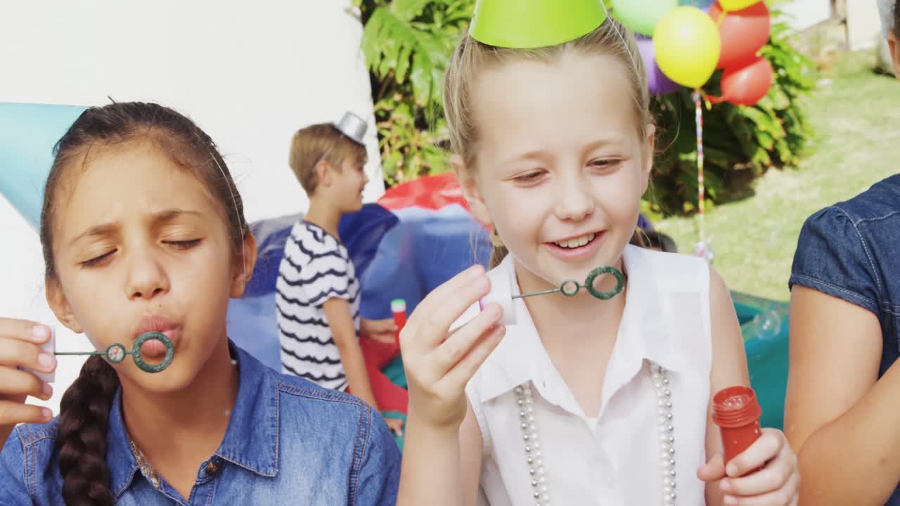 Amici felici che giocano con la bacchetta per le bolle di sapone in giardino 4k