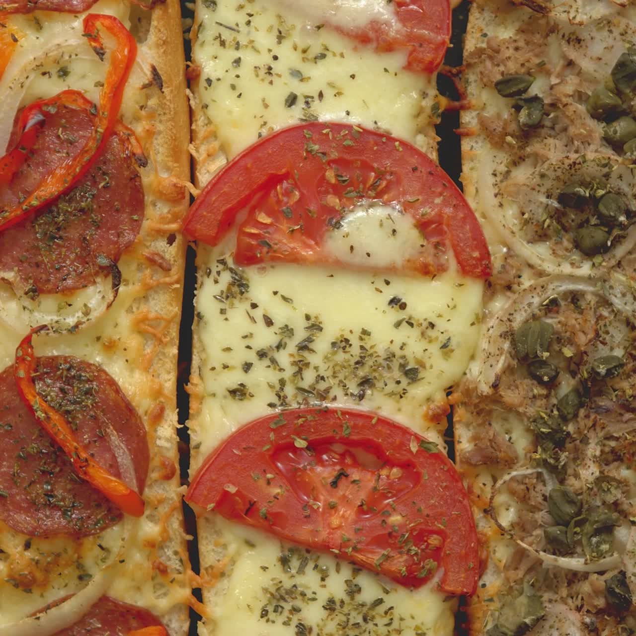 lange baguetter pizza sandwiches med tunfisk svampe tomater og ost på en metal baking bakke