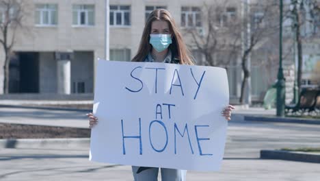 woman holding 'stay at home' sign