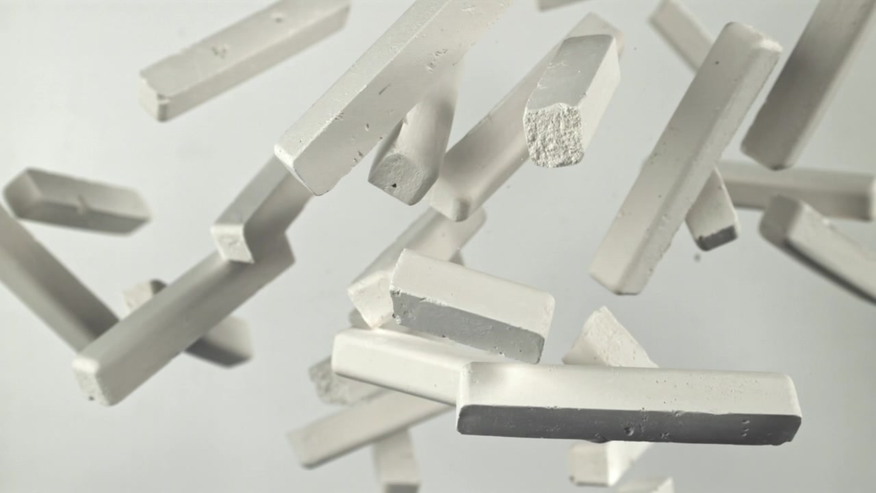 Pezzi di gesso bianco che fluttuano al rallentatore su sfondo chiaro