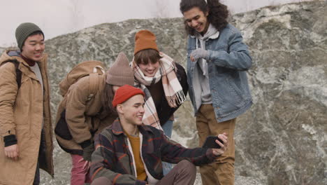 group of teenage friends dressed in winter clothes taking a selfie on the mountain