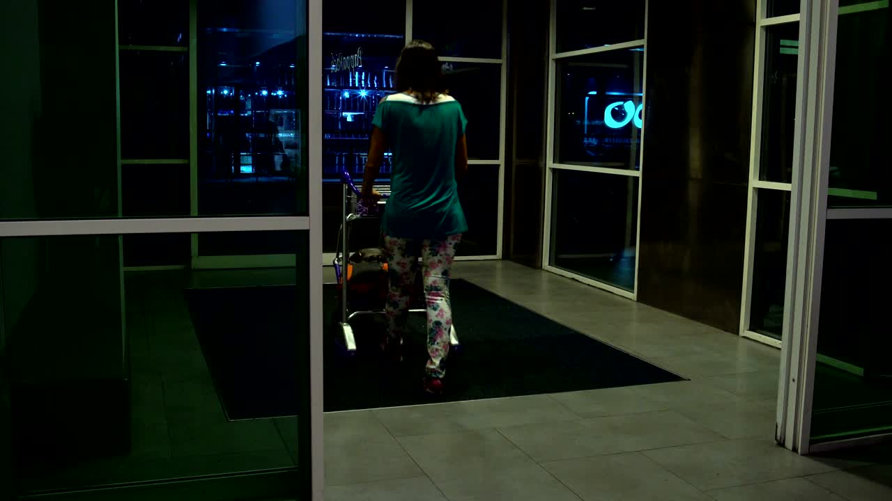 공항 의 자동 문 을 통해 가는 수하물 가방 을 들고 있는 여자