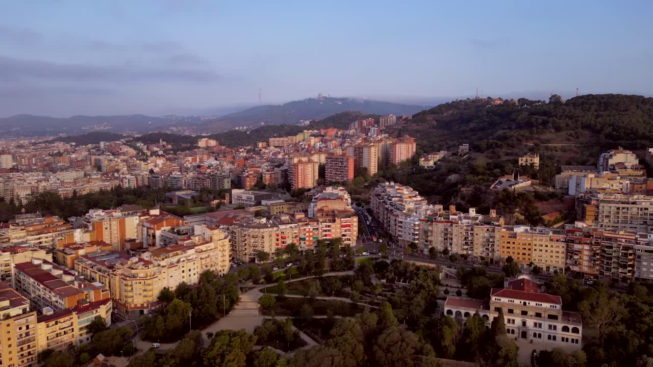 A cinematic aerial view of Catalonia's commercial and residential medium-rise building with a mountain view in the background