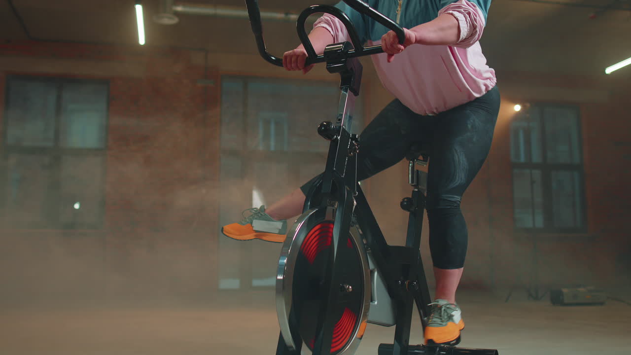 여성은 시 ⁇ 레이터, 사이클 트레이닝에서 유산소 지구력 훈련 운동 심장 루틴을 수행합니다.