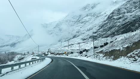 car driving on a road in skardu in landscape covered with snow and high mountains - it is cloudy