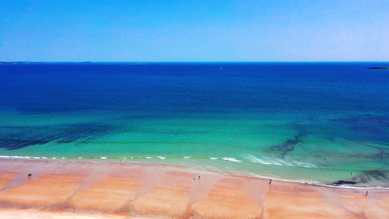 Saco, Maine peak-season drone shot: beaches alive with tourists and families. Sand full of people, blue Atlantic waves crash, vacation homes stand watch. A beautiful coastal view in New England