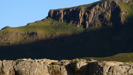 TIMELAPSE:-Sunny-morning,-alternating-sunlight-and-shadow-reveals-sandstone-mountain-cliffs-and-green-grass-in-Lesotho-Drakensberg-near-Sehlabathebe