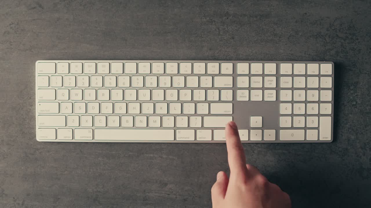 Hand Pressing a Key on a White Keyboard