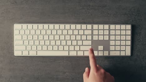 la mano presionando una tecla en un teclado blanco
