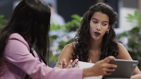 diverse female colleagues in discussion using tablet in casual office meeting, slow motion