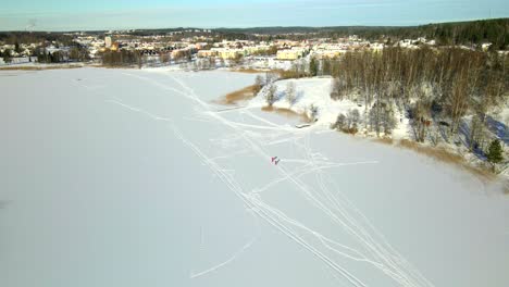 Zwei-Personen-Skifahren-Auf-Einem-Zugefrorenen-See-An-Einem-Kalten,-Sonnigen-Tag