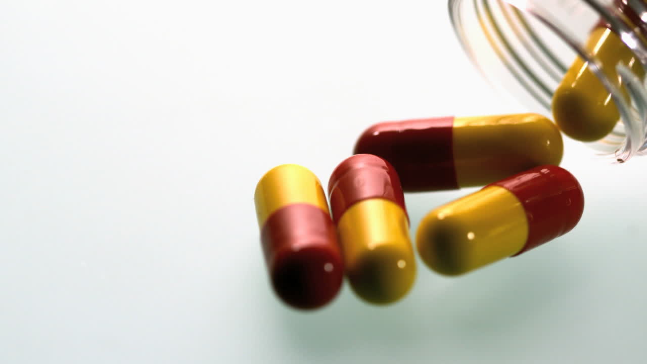 la cápsula de medicamento que se vierte de un frasco de plástico