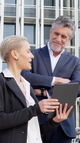 business professionals discussing on tablet outdoors