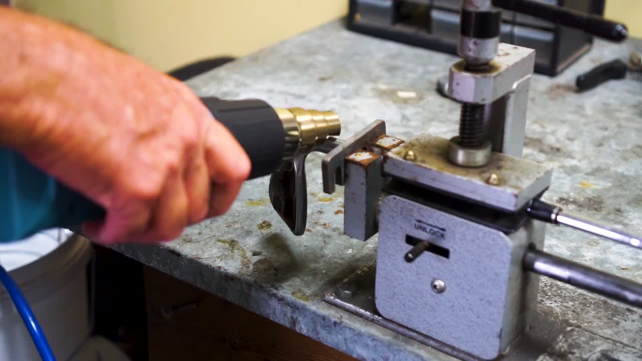 cámara lenta del hombre calentando la cabeza del palo de golf en abrazadera-vice