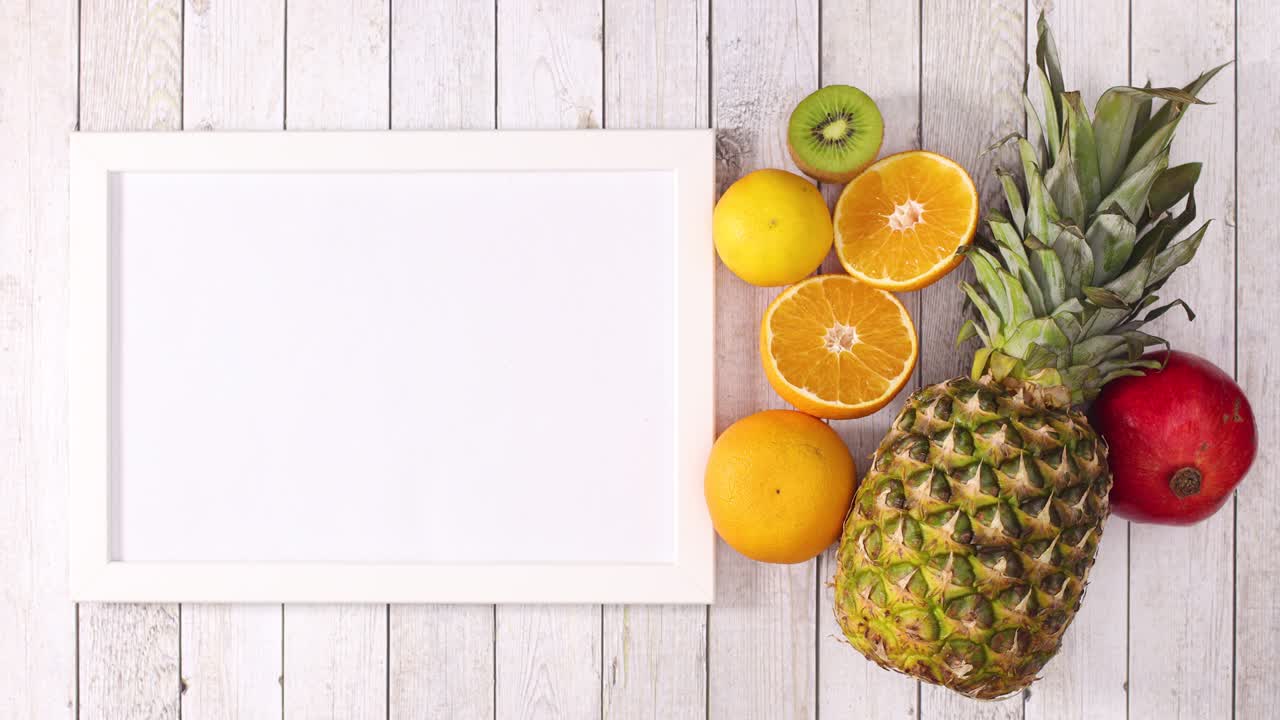 Pineapple, kiwi, orange and pomegranate appear with frame on wooden theme. Stop motion