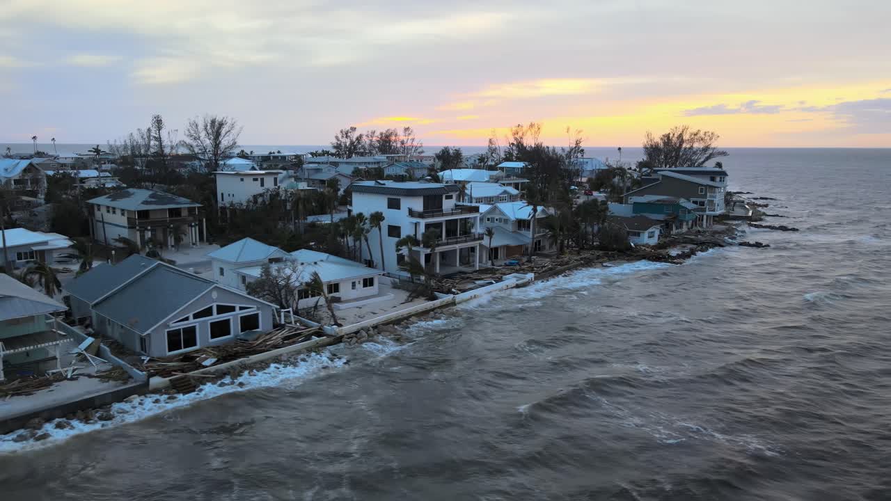 Aerial of Anna Maria Island, Florida at sunset revealing hurricane damage to waterfront homes. Orbit Right Sunset W