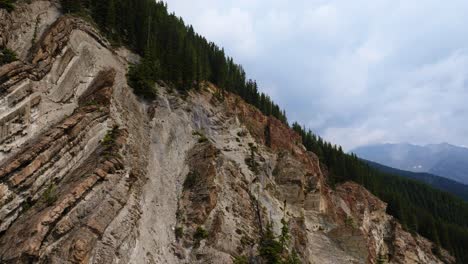 Drone-flying-up-steep-jagged-mountain-rock-face-in-Canadian-wilderness